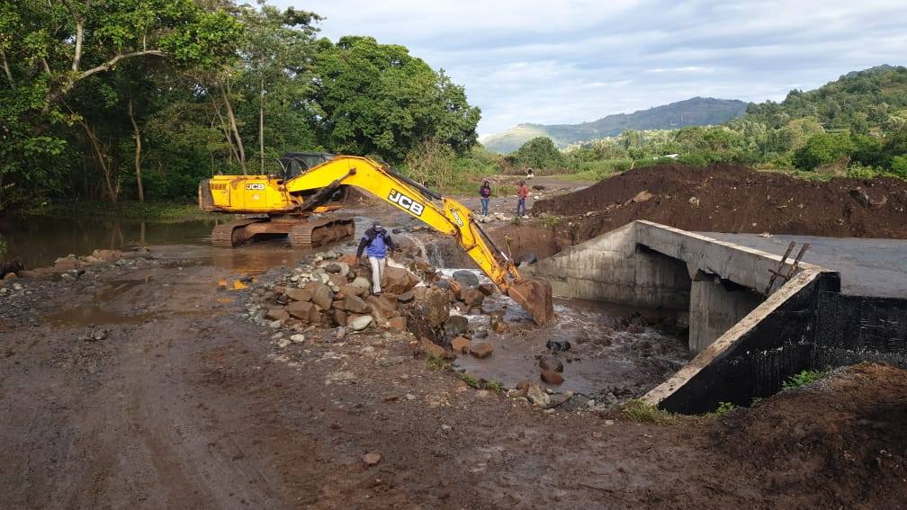 Excavator carrying out civil earthworks beside a river and concrete culvert