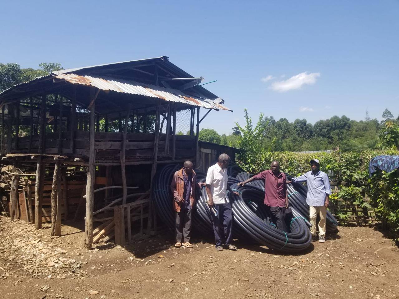 Community members standing beside coils of HDPE water pipe delivered for a pipeline extension