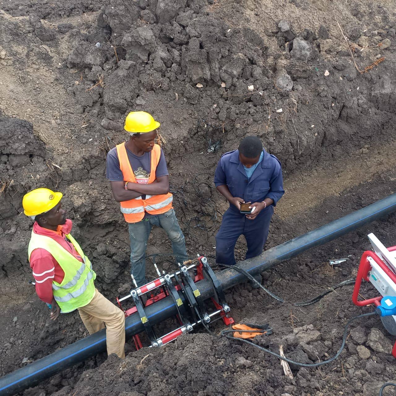 Technicians fusion-welding an HDPE water pipe in an open trench