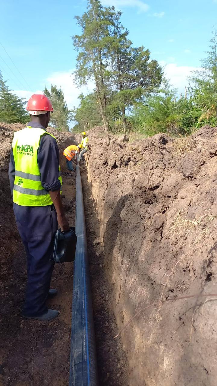 Supervisor overseeing water pipe laying in a long excavated trench