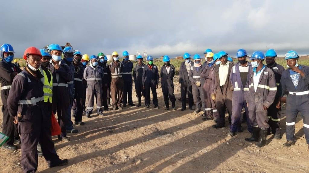 Scabbard site team in hard hats and reflective overalls at a safety briefing